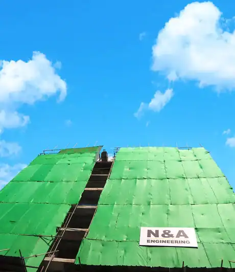 Construction site covered with green safety netting, showcasing NA Group's engineering expertise and safety standards.